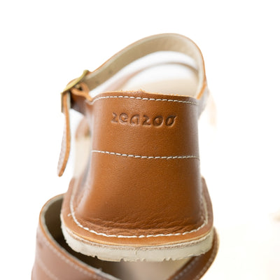 Brown Zeezoo Siren leather Sandals. The sandals have a front foot strap, a leather ankle strap, and a heel cup. Right shoe heel cup is shown close up stacked on the left shoe against a white background. #color_brown