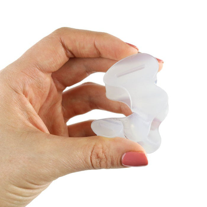A photo of correct toes clear toe spacers made from silicone. A woman holds one  correct toes toe spacer in her left hand and her nails are painted pink against a white background. 