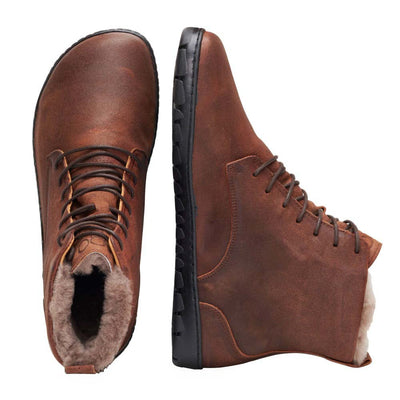 A photo of Zaqq Quintic boots made nappa leather, wool, and rubber soles. The boots are brown in color with dark brown laces and a wool lining inside. Both boots are shown from above the left boot is facing upright and the right boot is lying on its right side against a white background. #color_brown
