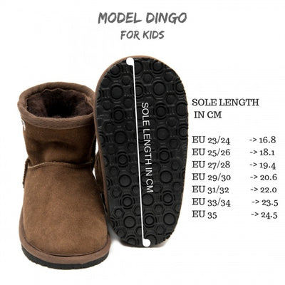 A photo of kids Zeezoo dingo boots made with suede lined with sheepskin and rubber soles. The boots are brown in color and they go around the mid calf. Both boots are shown beside each other the left boot is shown laying on it’s back to show the sole the size chart is shown on the side against a white background. #color_brown