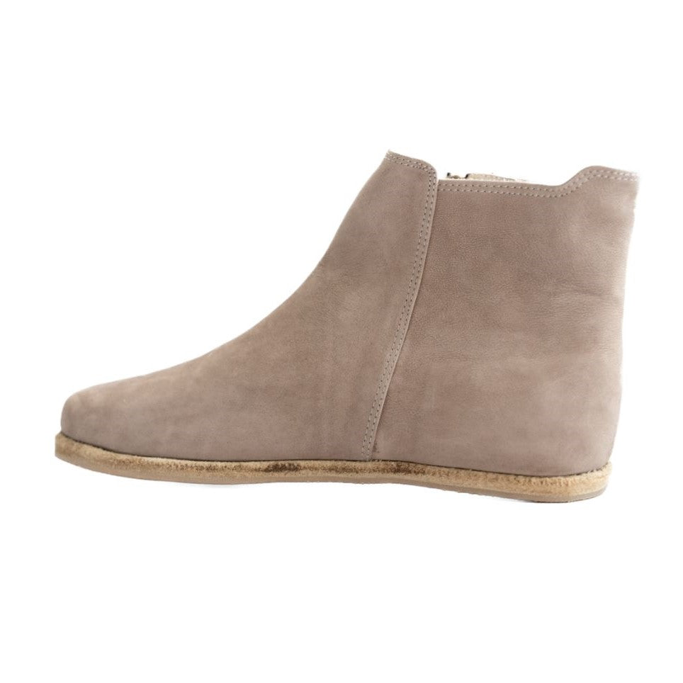 A photo of designed by Anya Rosa boots made from nubuck leather and rubber soles. The boots are taupe in color, they are a Chelsea boot style with a zipper on the sides. One boot is shown from the left side against a white background. #color_taupe-nubuck