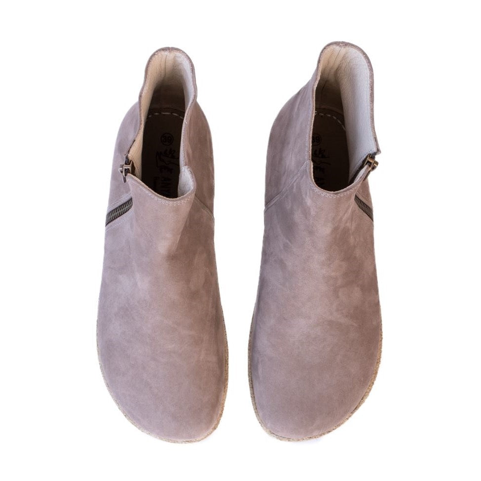 A photo of designed by Anya Rosa boots made from nubuck leather and rubber soles. The boots are taupe in color, they are a Chelsea boot style with a zipper on the sides. Both boots are shown beside each other from above against a white background. #color_taupe-nubuck