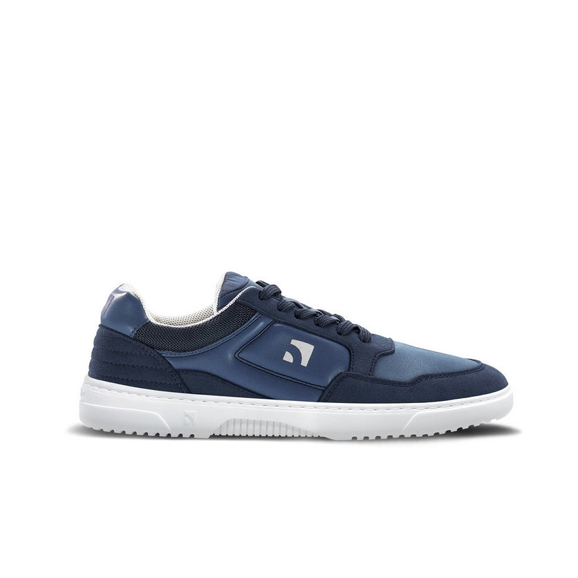 Photo 1 - A photo of Barebarics Axiom sneakers. The sneakers are made with a dark blue tent-like fabric with suede-like material borders around the toe box, laces, ankle, and heel. The rubber sole is white and there is a logo on the wide of the shoe. Left sneaker is shown here from the right side against a white background., Photo 2 - Both shoes are shown from the top down against a white background. #color_dark-blue-white
