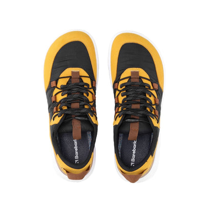 Photo 1 - A photo of Barebarics Revive sneakers. The sneakers are made of a black tent-like fabric with golden yellow suede-like material borders around the toe box, laces, ankle, and heel. Decorative thin elastic laces lay overtop of the fabric laces. The rubber sole is white and there is a logo on the side of the shoe. Right sneaker is shown here from the right side against a white background., Photo 2 - Both shoes are shown from the top down against a white background. #color_golden-yellow-black