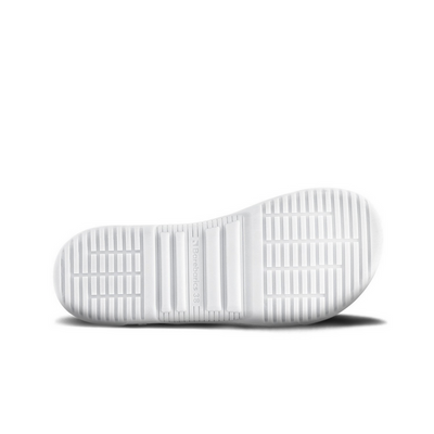 A photo of Barebarics Zing sneakers made with a leather upper and a rubber sole. The sneakers are a white and beige color with perforated spots on the top of the toe box and barebarics branding on the tongue and side. They also have black at the top of the heel. The left shoe is shown from the sole to show the detail against a white background. #color_white-beige