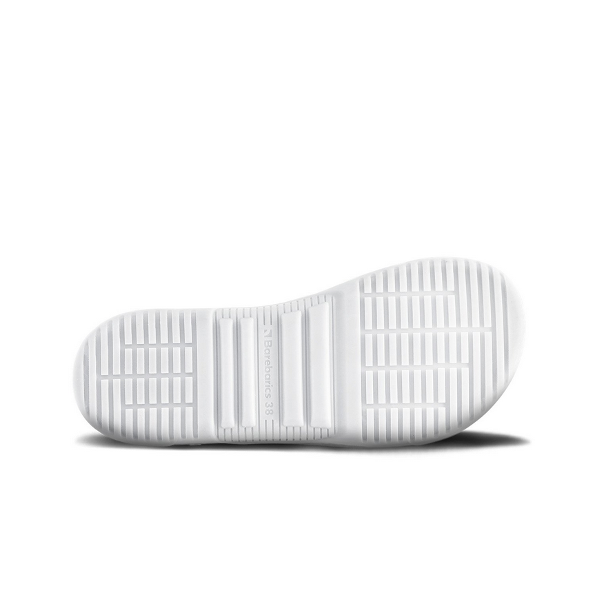 A photo of Barebarics Zing sneakers made with a leather upper and a rubber sole. The sneakers are a white color with perforated spots on the top of the toe box and barebarics branding on the tongue and side. The left shoe is shown from the sole to show the detail against a white background. #color_white