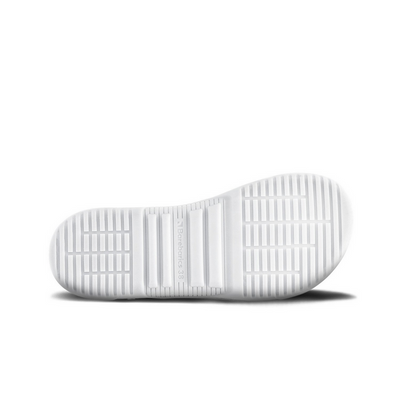 A photo of Barebarics Zing sneakers made with a leather upper and a rubber sole. The sneakers are a white color with perforated spots on the top of the toe box and barebarics branding on the tongue and side. The left shoe is shown from the sole to show the detail against a white background. #color_white