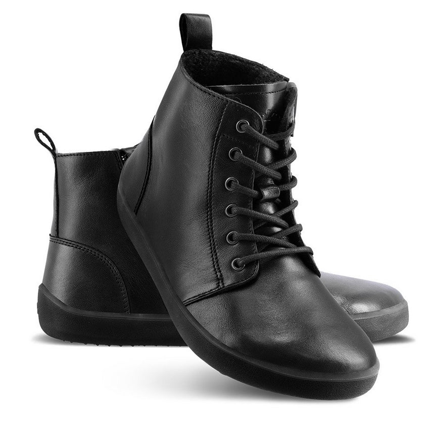A photo of Be Lenka Atlas ankle zip up boots made from smooth leather and rubber soles. The boots are black in color with black laces, zippers, a pull tab in the back, and lined with felt. Left boot shown from the left side with the right boot's heel resting diagonally on the left against a white background. #color_black