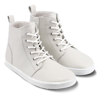 A photo of Be Lenka Atlas ankle zip up boots made from smooth leather and rubber soles. The boots are cream in color with white laces, zippers, a pull tab in the back, and lined with felt. Both boots are shown diagonally from the right side against a white background. #color_black