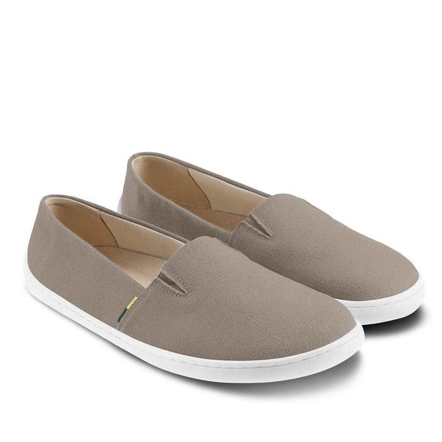 A photo of Dark Khaki Be Lenka Bali canvas loafers with rubber soles. The loafers have two V-shaped stitching details at the top opening of the shoe. Both shoes are shown with the left shoe facing right and the right shoe heel propped up on the left shoe against a white background. #color_dark-khaki
