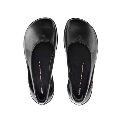 A photo of Be Lenka Bellissima flats with a leather upper and rubber soles. The flats are a black color with a small stitching V detail in the front and a cut out design on the sides. Both flats are shown from above facing upright against a white background. #color_black