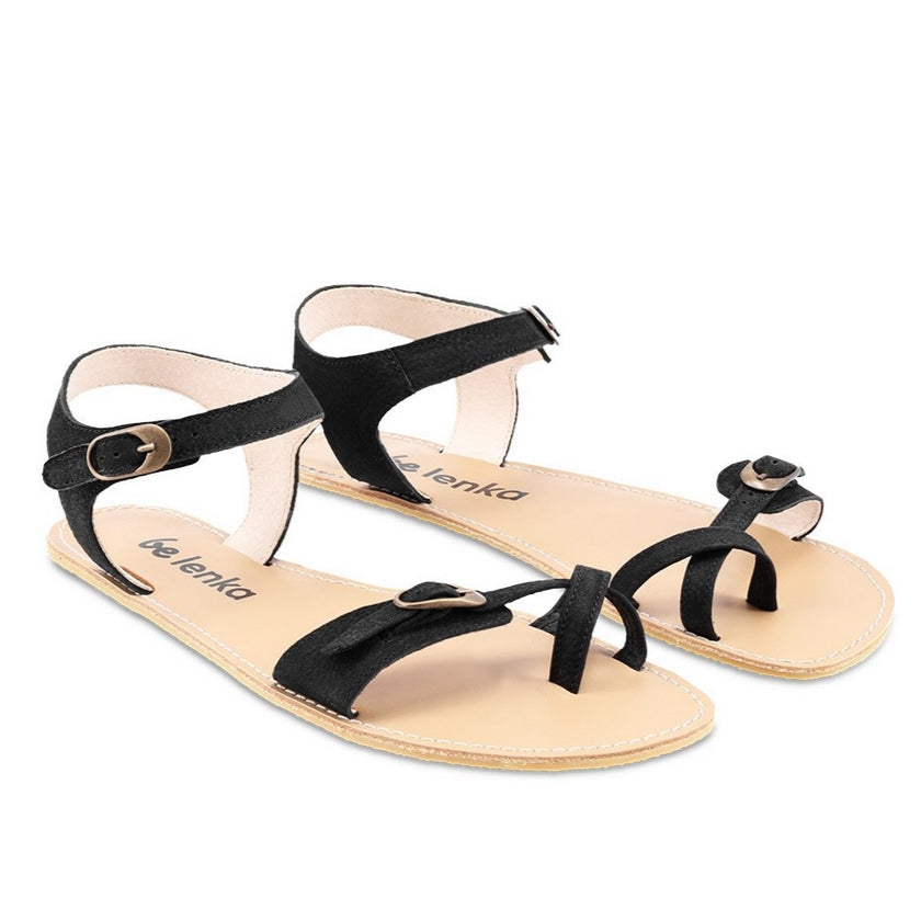 Photo 1 - Be Lenka Claire leather sandals in black. Sandals have an open heel ankle strap that closes with a gold buckle, and connects to both sides of the sole. A criss-cross toe strap is featured at the big toe with a gold buckle connecting a thin toe strap to a thicker strap on the outside. Shoes are shown diagonally from the right side with a white background., Photo 2 - Both shoes are shown from the top down against a white background. #color_black