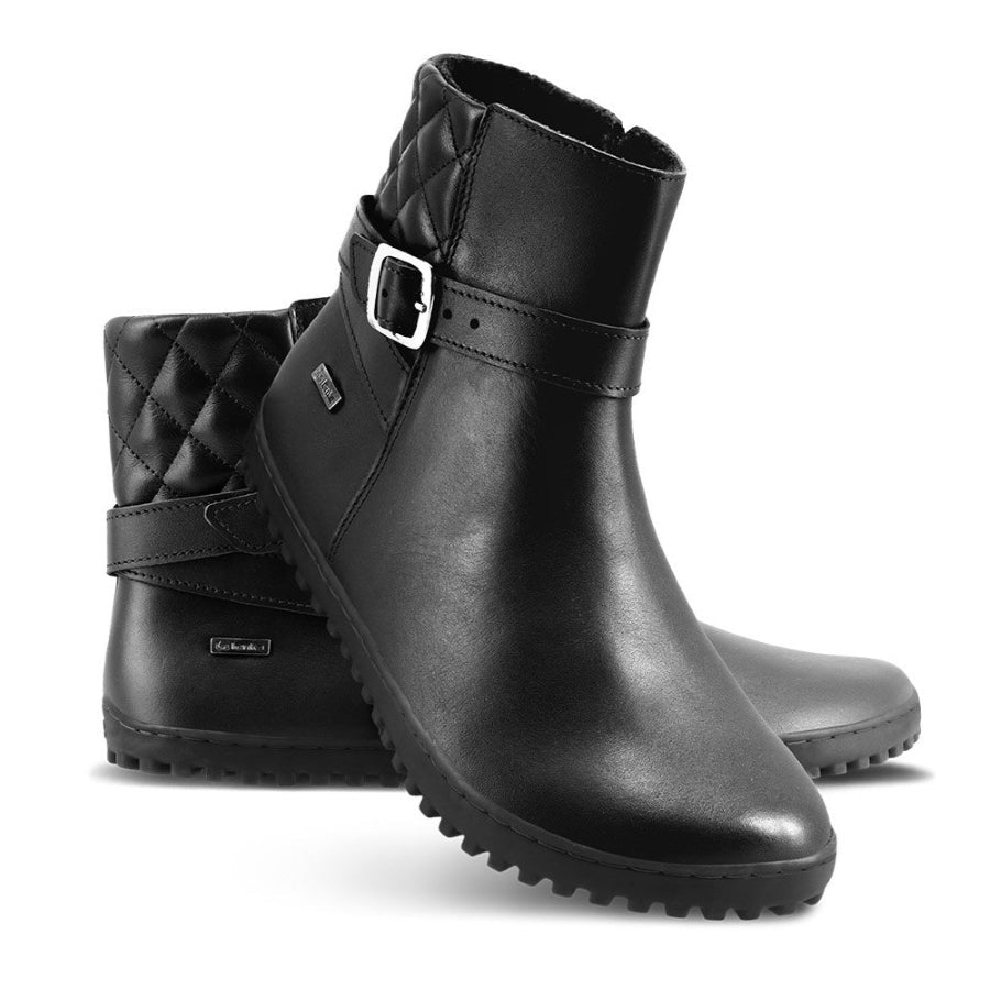A photo of Be Lenka Diva boots in all black. Boots are made from smooth black leather. A quilted leather design is present in the back, a silver buckle on the side, a strap around the ankle, and a zipper. Left shoe is shown from the right side with the left boot propped up against it with a white background. #color_all-black