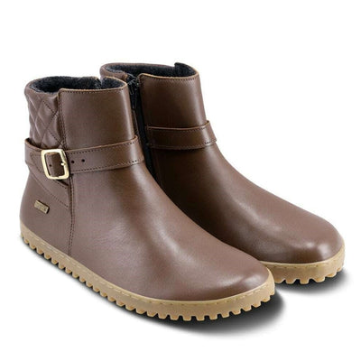 A photo of Be Lenka Diva boots in dark brown with tan soles. Boots are made from dark brown leather. A quilted leather design is present in the back, a silver buckle on the side, a strap around the ankle, and a zipper. Both shoes are shown diagonally from the front right against a white background. #color_dark-brown