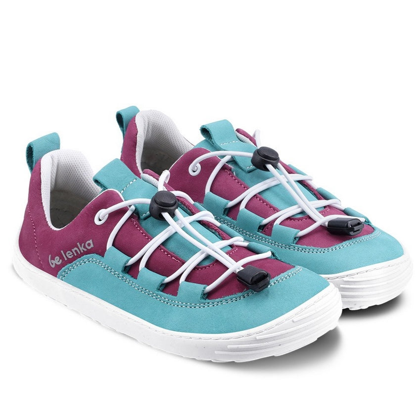 A photo of Be Lenka Xplorer kids shoes in light teal and plum nubuck leather with white soles and laces. The plum color goes from the heel to the front of the shoe with a teal tongue, pull tab, and around the side and front edges of the toe box. White elastic laces are laced through teal tabs attached to the teal leather accents on sides and end at the plum color on either side of the tongue. #color_light-teal-plum