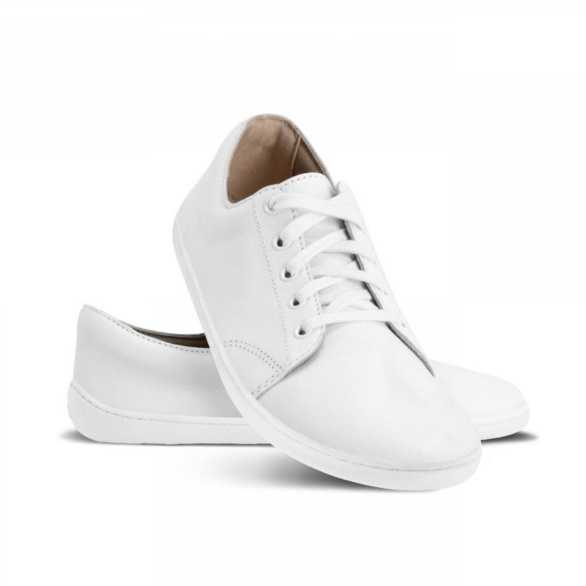 A photo of White Be Lenka Prime 2.0 Simple Leather Sneakers with white soles. Left shoe is shown from the right with the right shoe propped up on the left to show the top of the shoe. Background is white. #color_white