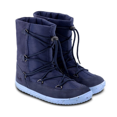 A photo of Be Lenka Kids Snowfox boots in dark and light blue. Dark blue suede and textile and light blue soles surround the outside. Dark blue laces are widely connected from side to side starting at the ball of the foot and going until the top of the boot with a quick lace connector securing the laces in place. Both shoes are shown diagonally from the front right side against a white background. #color_dark-light-blue