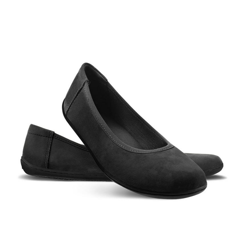 A photo of Matte Black Be Lenka Sophie Simple Leather flats with black soles. Left shoe is shown from the right with the right shoe propped up on the left to show the top of the shoe. Background is white. #color_matte-black