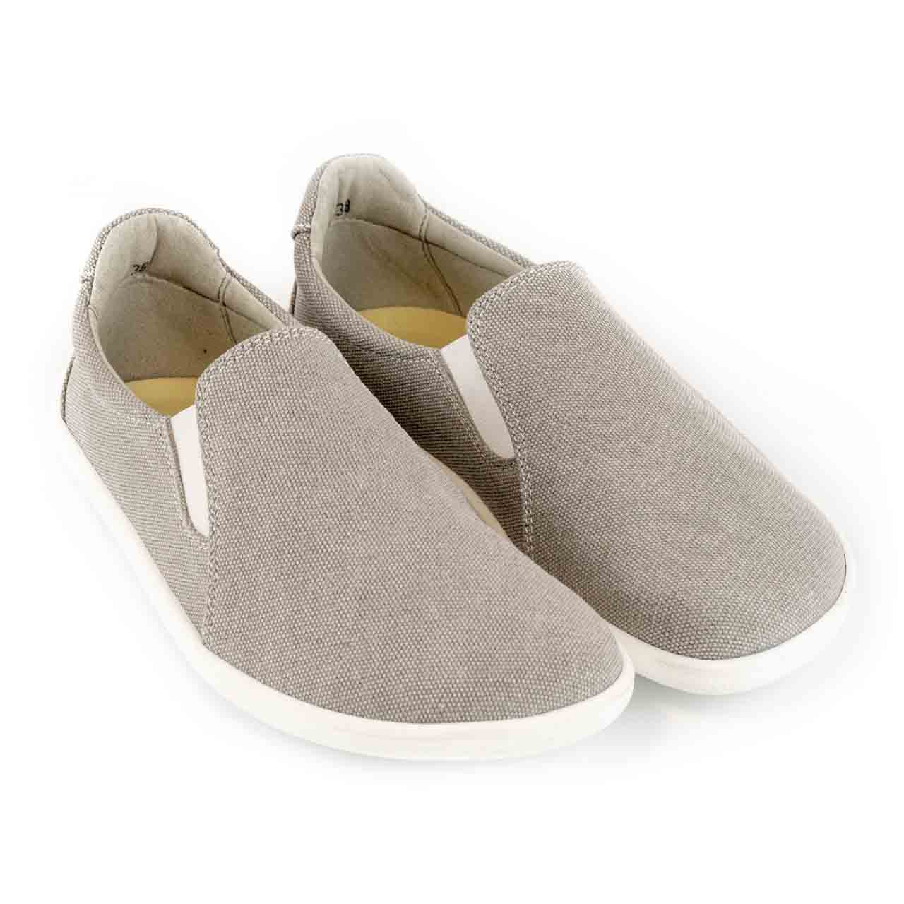 A photo of Belenka Eazy slip-on sneakers made from canvas and rubber soles. The sneakers are a sand color with white elastic on the sides and soles. Both shoes are shown beside each other facing the front and slightly angled to the right against a white background. #color_sand
