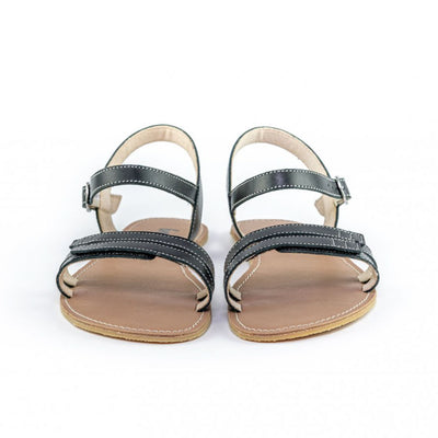 A photo of Black Be Lenka Summer Sandals made with leather and tan rubber soles. The sandals are black and have thin double straps on the front of the foot. They also have straps that go around the ankle and heel and have a small buckle. Both sandals are shown from the front beside each other against a white background in this photo. #color_black
