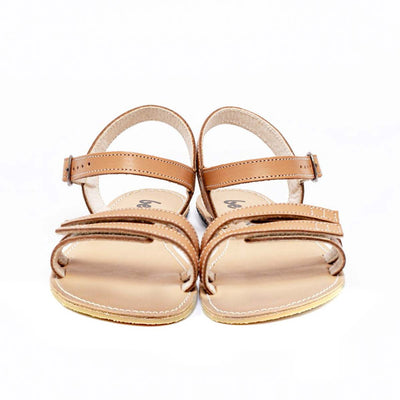 A photo of Brown Be Lenka Summer Sandals made with leather and tan rubber soles. The sandals are medium brown in color and have thin double straps on the front of the foot. They also have straps that go around the ankle and heel and have a small buckle. Both sandals are shown from the front beside each other against a white background in this photo. #color_brown
