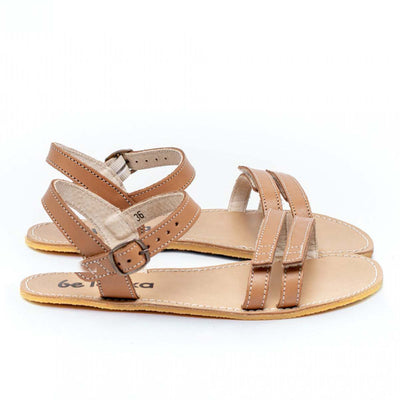 A photo of Brown Be Lenka Summer Sandals made with leather and tan rubber soles. The sandals are medium brown in color and have thin double straps on the front of the foot. They also have straps that go around the ankle and heel and have a small buckle. Both sandals are shown from the right side against a white background in this photo. #color_brown