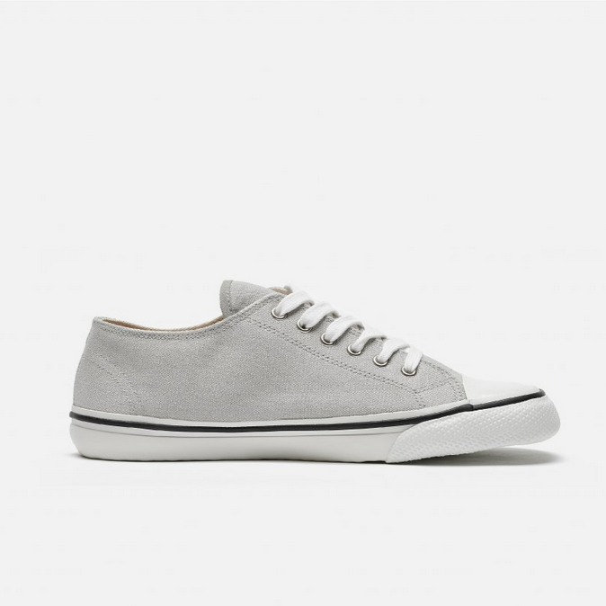 A photo of Bohempia Herlik canvas sneakers made from canvas and rubber soles. The sneakers are light grey with a white toe cap and a black outline around the white rubber soles. The left sneaker is shown from the right side on a white background. #color_light-grey-white