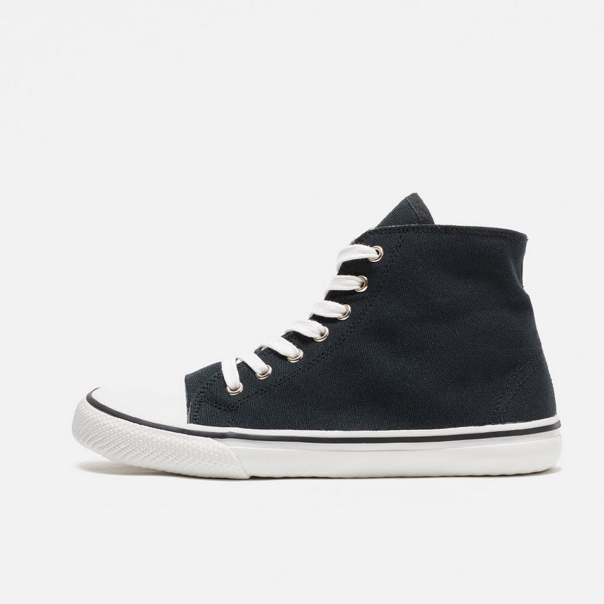 A photo of Bohempia Orik canvas high tops made from canvas and rubber soles. The sneakers are a black color with a white toe cap and a black outline around the rubber. The left sneaker is shown from the left side against a white background. #color_black-white