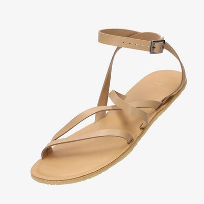 A photo of beige leather Groundies Florence Sandals. Two leather straps start at the ball of the big toe with one ending at the ball of the little toe and the other midfoot. Another strap goes from one side of the heel over the top of the foot to the other side with one final strap wrapping around the ankle and closing with a buckle. Shoe is shown floating diagonally from the front left side against a white background. #color_beige