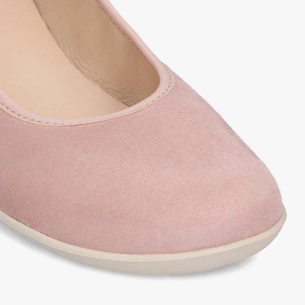 A photo of Groundies Lily Soft flats with a leather upper and cream rubber true sense soles. The flats are a nubuck in a light pink color, the trim around the tops of the flats is a light pink color that is lighter than the rest of the flats. The interior of the flats is a light beige color. The right flat is shown up close from the front angled to the right against a white background. #color_light-pink