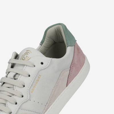A photo of Groundies Nova sneakers made from leather and rubber soles. The sneakers are beige and white with pink/green accents on the heel, they also have perforation on the toe box. One sneaker is shown floating up close towards the back of the shoe to show detail against a white background. #color_beige-green-pink