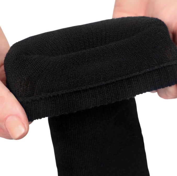 A photo of Knitido essential midi crew toe socks made with cotton, nylon, and elastane. The socks are a black color. A woman’s hands are shown up close stretching the top of the socks while they are folded over against a white background. #color_black