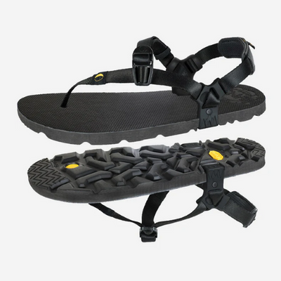 A photo of Luna Mono Winged Black Adventure Sandals made from a monkey grip technology footbed and a rubber sole. The sandals have a thong toe strap with straps that go around the ankle and heel. The sandals have a logo moon on the thong toe strap and luna logo on the heel and right ankle strap. Both sandals are shown floating over top each other with a space in between the left sandals is on top and the right sandal is flipped upside down below against a white background. #color_black