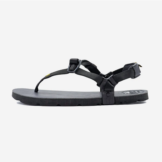 A photo of Luna Mono Winged Black Adventure Sandals made from a monkey grip technology footbed and a rubber sole. The sandals have a thong toe strap with straps that go around the ankle and heel. The sandals have a logo moon on the thong toe strap and luna logo on the heel and right ankle strap. The left sandal is shown from the left side against a white background. #color_black