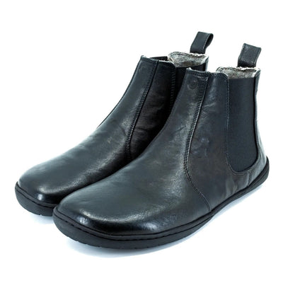 A photo of Mukishoes felted-wool-lined, leather Chelsea boots in black. Boots have elastic pannels on both sides of the shoe and a pull tab at the top of the ankle opening. Soles are black in color and are stitched to the leather. Both boots are shown here diagonally from the front left side against a white background. #color_black