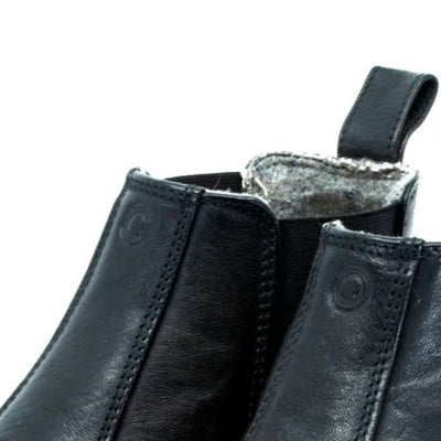 A photo of Mukishoes felted-wool-lined, leather Chelsea boots in black. Boots have elastic pannels on both sides of the shoe and a pull tab at the top of the ankle opening. Soles are black in color and are stitched to the leather. The right boot ankle opening is shown close up here from the front against a white background. #color_black