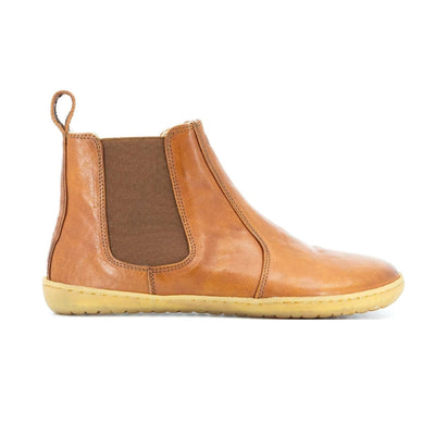 A photo of Mukishoes felted-wool-lined, leather Chelsea boots in caramel. Boots have brown elastic pannels on both sides of the shoe and a pull tab at the top of the ankle opening. Soles are a natural gum rubber color and are stitched to the leather. The right boot is shown here from the right side against a white background. #color_caramel