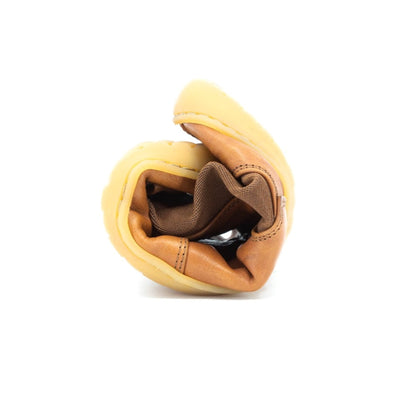 A photo of Mukishoes felted-wool-lined, leather Chelsea boots in caramel. Boots have brown elastic pannels on both sides of the shoe and a pull tab at the top of the ankle opening. Soles are a natural gum rubber color and are stitched to the leather. The boot is shown here rolled into a ball against a white background. #color_caramel