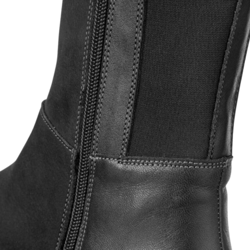 A photo of Peerko Regina riding boots made from smooth leather and rubber soles. The boots are black in color with a tall riding boot elastic paneled shaft, zippers, and lined with felt. Right boot is shown close up to the zipper and elastic pannels against a white background. #color_black