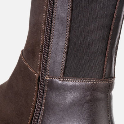 A photo of Peerko Regina riding boots made from smooth leather and rubber soles. The boots are brown in color with a tall riding boot elastic paneled shaft, zippers, and lined with felt. Right boot is shown close up to the zipper and elastic pannels against a white background. #color_brown
