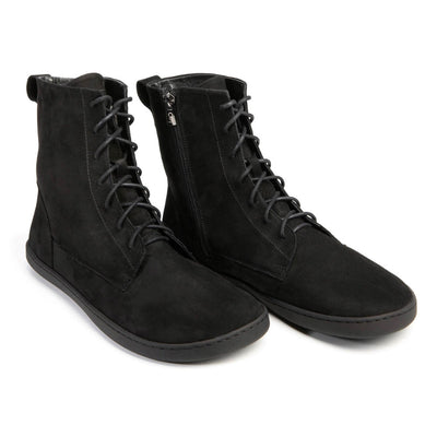 A photo of the Shapen Cozy lace up boots made from a water resistant nubuck leather upper, wool lining, and black rubber soles. The boots are black in color with black laces and have a zipper on the inner side. Both boots are shown together from the front right side on a white background. #color_black