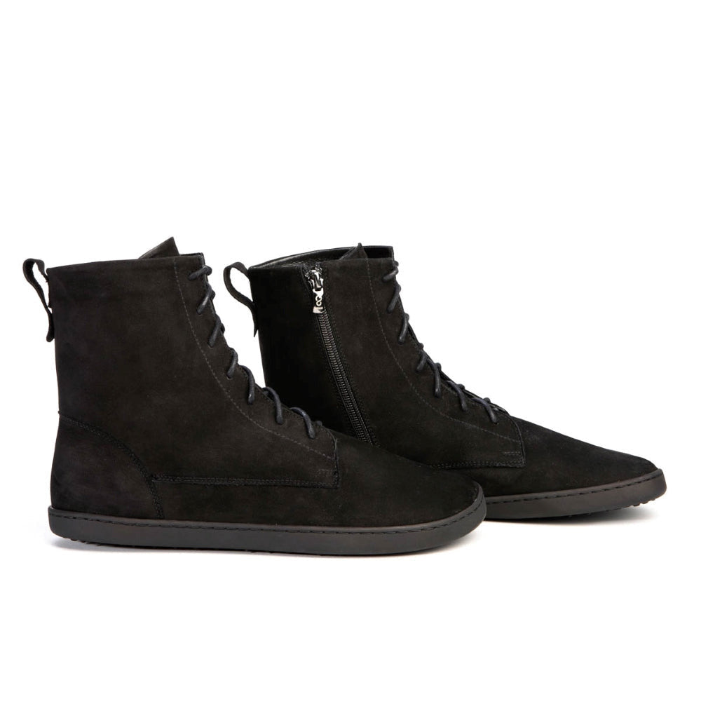 A photo of the Shapen Cozy lace up boots made from a water resistant nubuck leather upper, wool lining, and black rubber soles. The boots are black in color with black laces and have a zipper on the inner side. Both boots are shown from the right side on a white background. #color_black