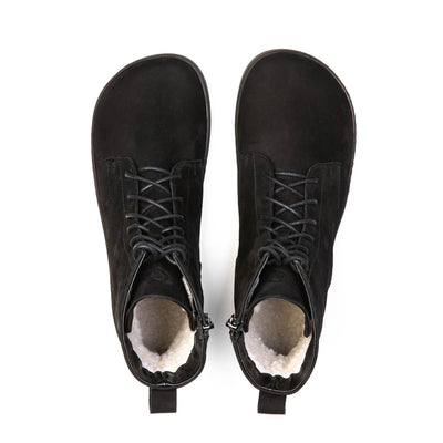 A photo of the Shapen Cozy lace up boots made from a water resistant nubuck leather upper, wool lining, and blak rubber soles. The boots are black in color with black laces and have a zipper on the inner side. Both boots are shown together from above on a white background. #color_black