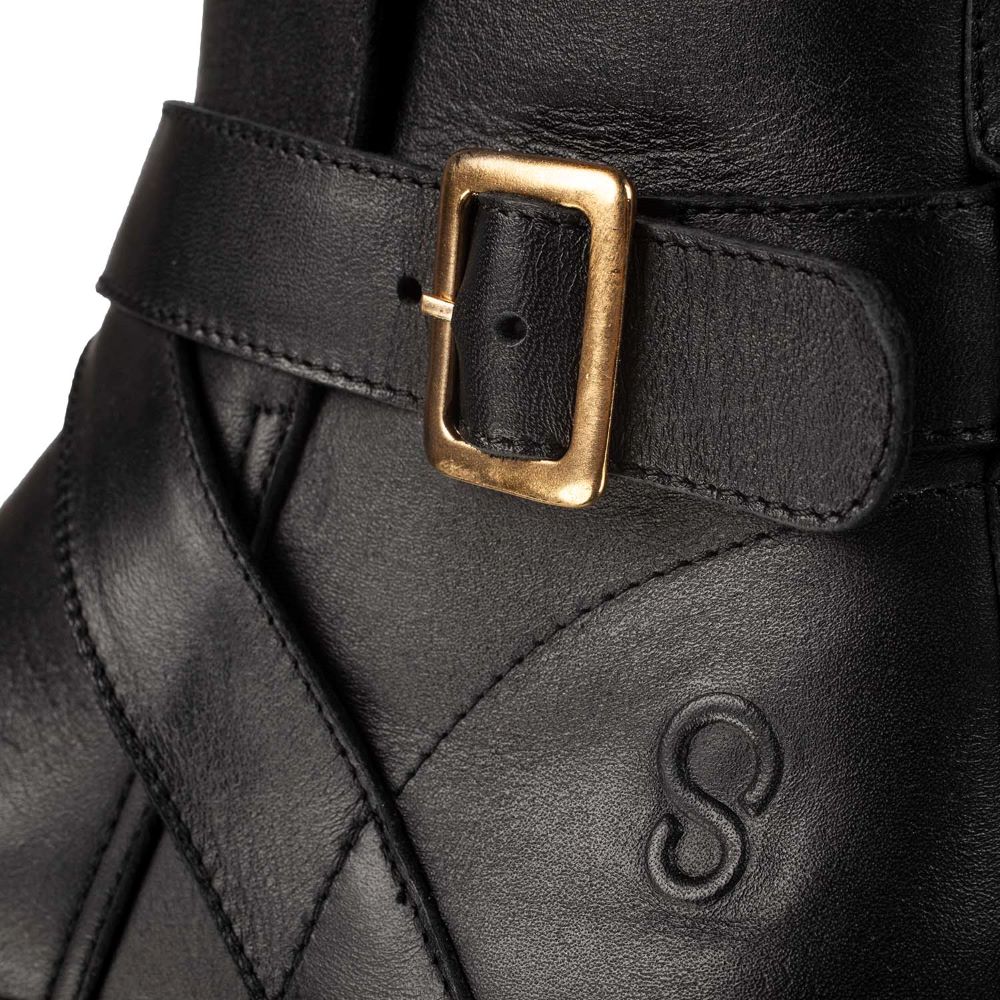 A photo of the Shapen Divine ankle boots made with a smooth leather upper, a microline lining, and rubber soles. The boots are black in color and have an ankle strap with a gold buckle, as well as a side zipper. The left boot is shown with a closeup of the buckle detail on a white background. #color_black