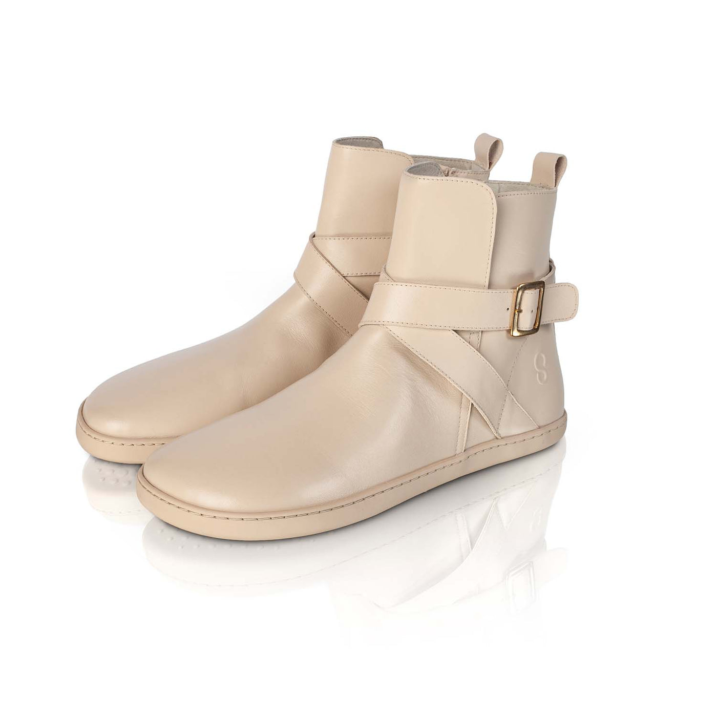 A photo of the Shapen Divine ankle boots made with a smooth leather upper, a microline lining, and rubber soles. The boots are vanilla in color and have an ankle strap with a gold buckle, as well as a side zipper. Both boots are shown together from the front left on a white background. #color_vanilla
