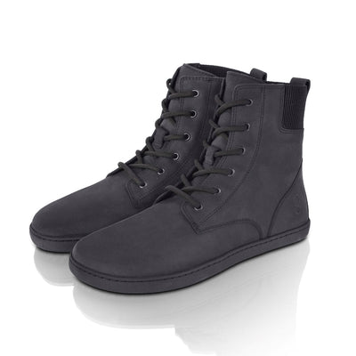 A photo of the Shapen Urbaneer combat boots made with nubuck leather, a thin wool lining, and rubber soles. The boots are black in color and have an elasticized panel on the top back of the boot. Both boots are shown together diagonally from the front left side on a white background. #color_black