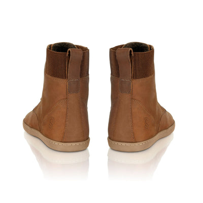A photo of the Shapen Urbaneer combat boots made with nubuck leather, a thin wool lining, and rubber soles. The boots are caramel brown in color and have an elasticized panel on the top back of the boot. Both boots are shown from behind to show the elasticized panel, on a white background. #color_caramel