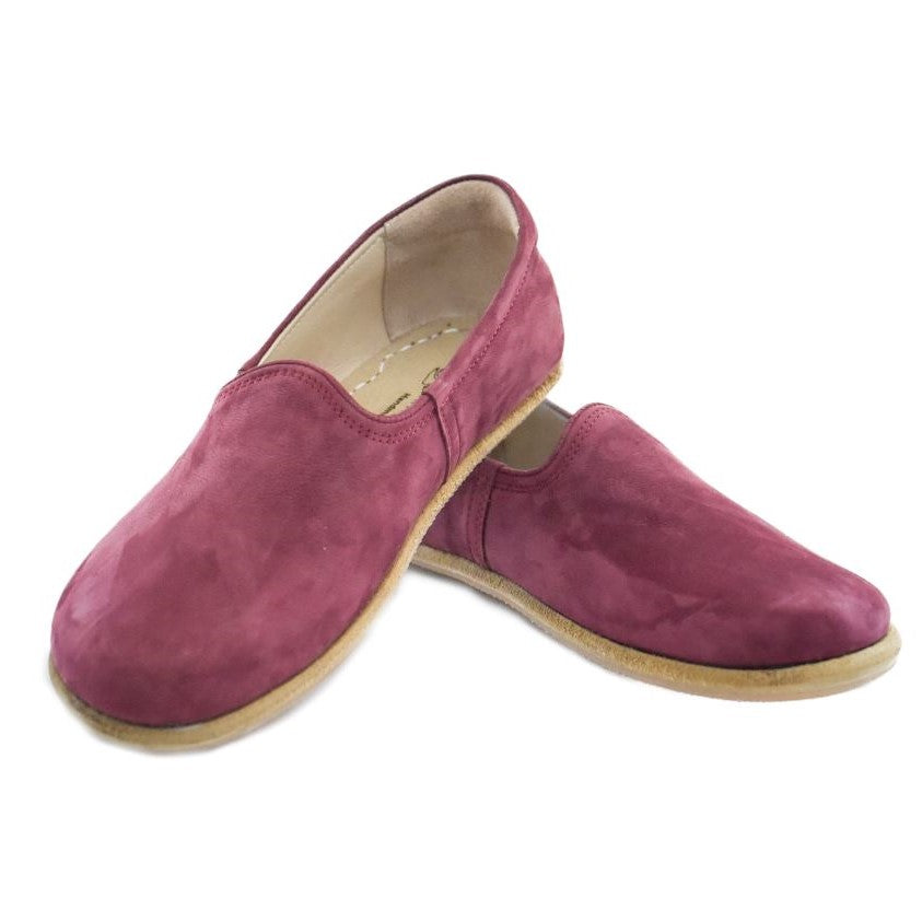 A photo of Yasemin Leather loafers Designed by Anya with a leather upper and tan rubber soles. The loafers are a mauve color with a nubuck leather upper and have a small curve up on the top of the foot for design. Both loafers are shown facing opposite directions with the heel of the right shoe is leaning on the left shoe against a white background. #color_mauve-nubuck