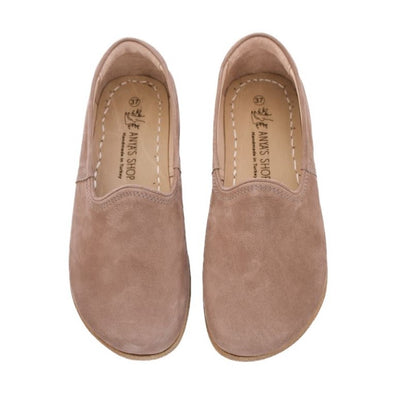 A photo of Yasemin Leather loafers Designed by Anya with a leather upper and tan rubber soles. The loafers are a taupe nubuck color and have a small curve up on the top of the foot for design. Both loafers are shown from the top facing down against a white background. #color_taupe-nubuck
