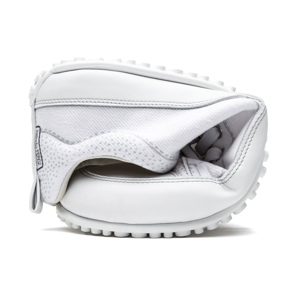 A photo of Zapato Feroz made from a textile upper and rubber soles. The sneakers are white in color with white stitching and white soles. One shoe is shown rolled into a ball to show the flexibility against a white background. #color_white